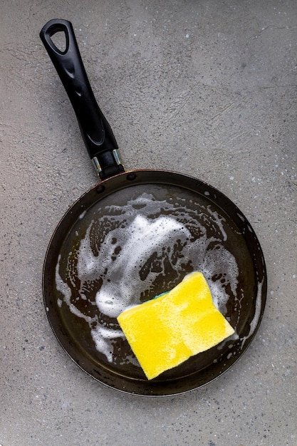 Sponge for washing dishes soap suds frying pan space for text
