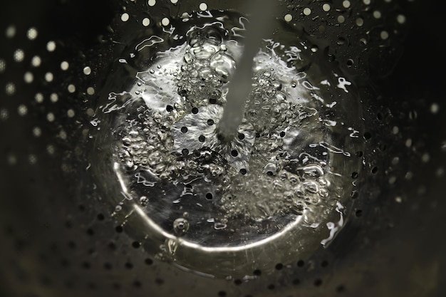 Water Pouring into Metal Colander HighResolution CloseUp of Splashing Liquid Through Holes