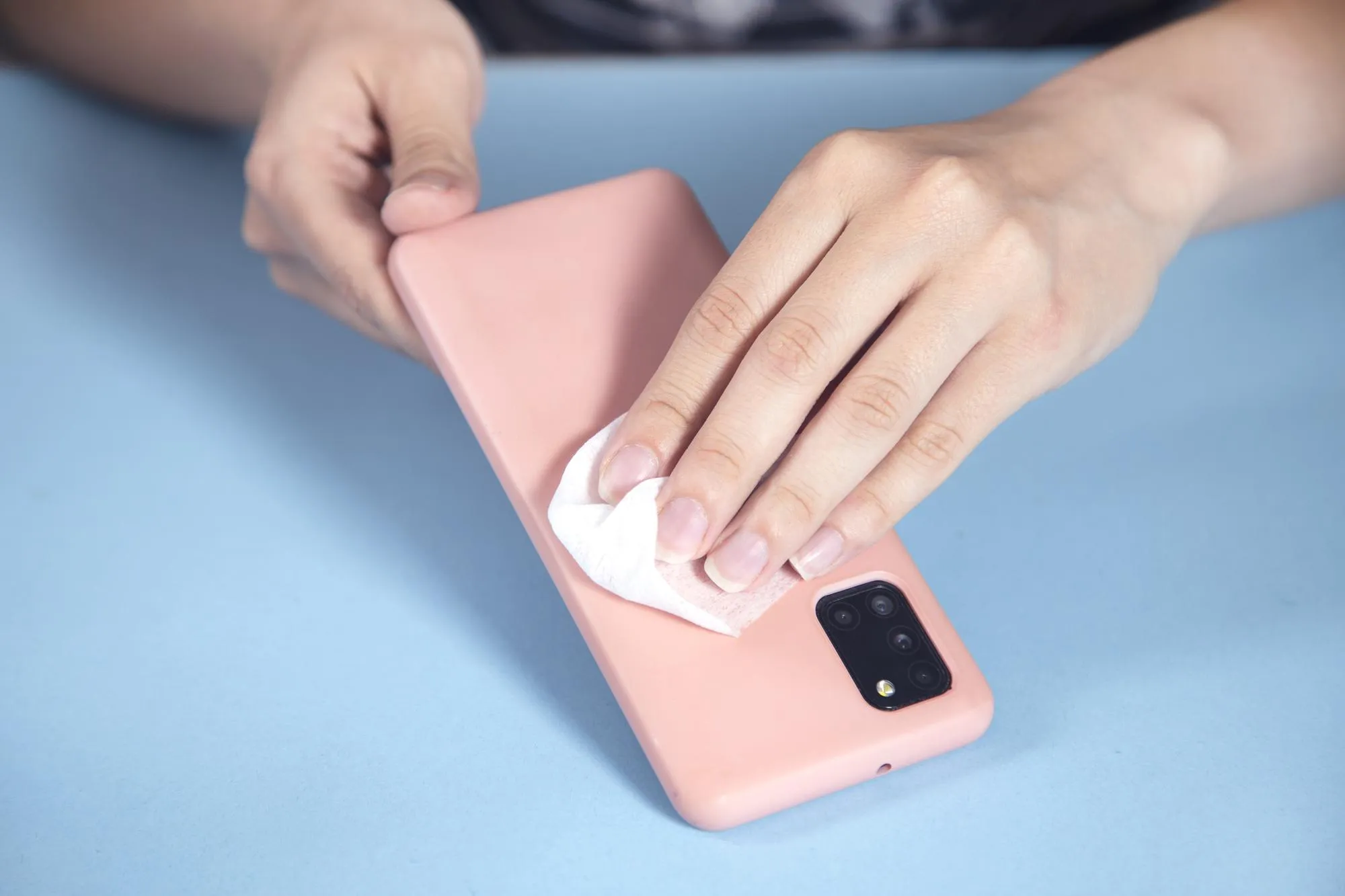 Woman cleaning phone in napkin