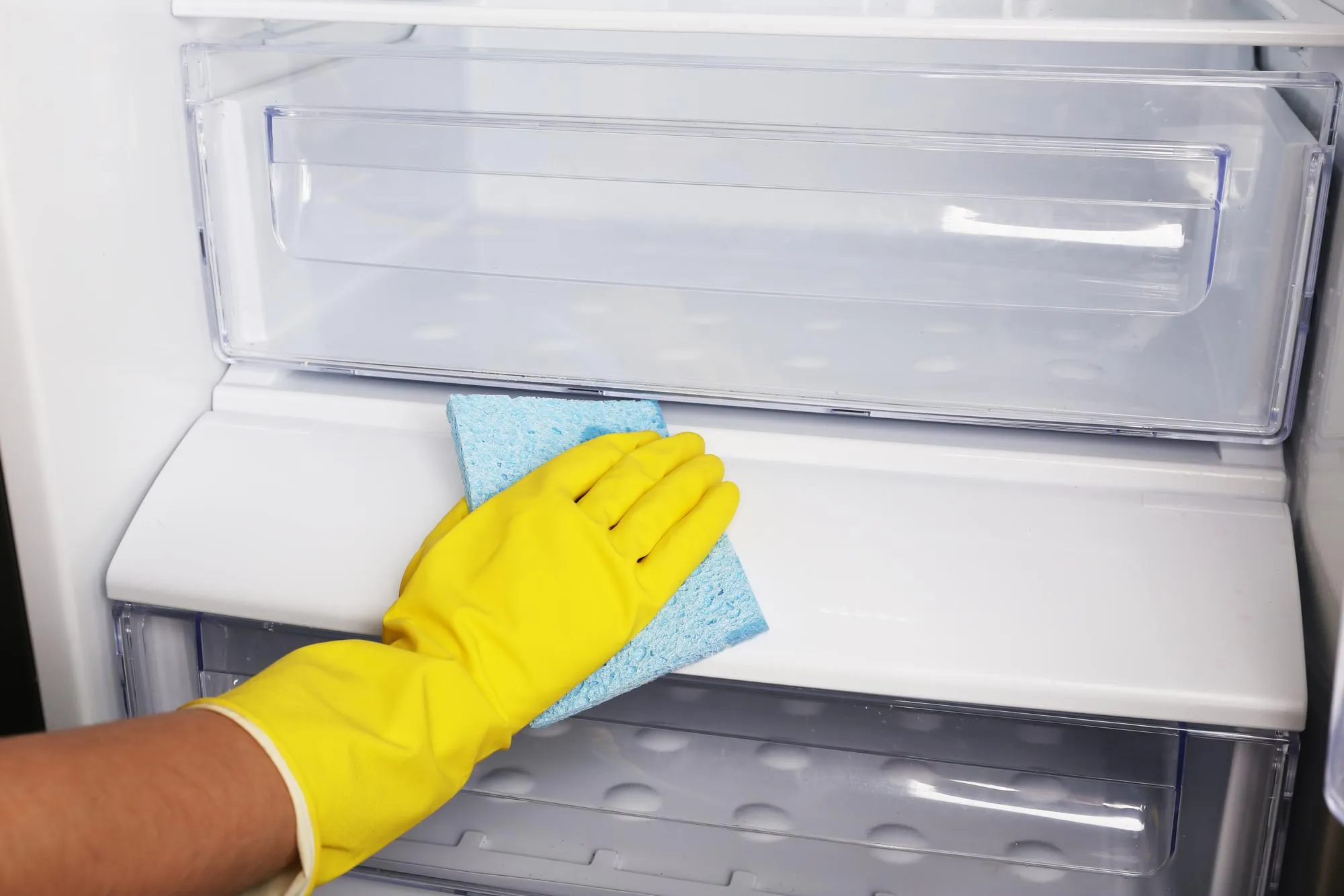 Woman's hand washing refrigerator with duster