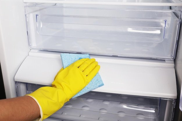 Woman's hand washing refrigerator with duster