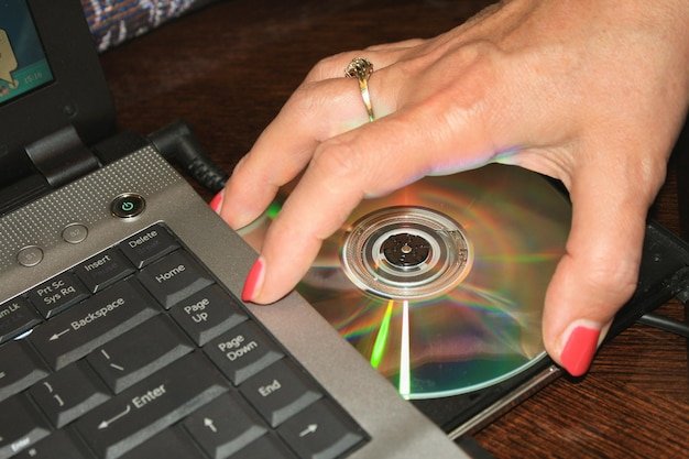 Womans hand taking DVD disc from laptop