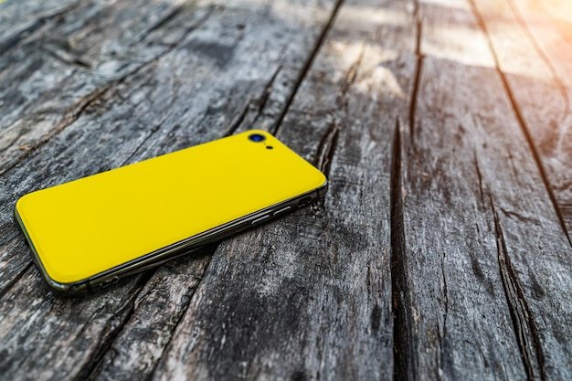 The yellow smartphone is on the background of wooden boards