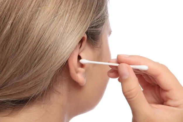 Young woman cleaning ear with cotton swab on white background closeup