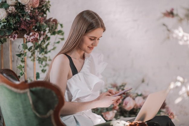 Young woman using mobile phone while sitting on laptop