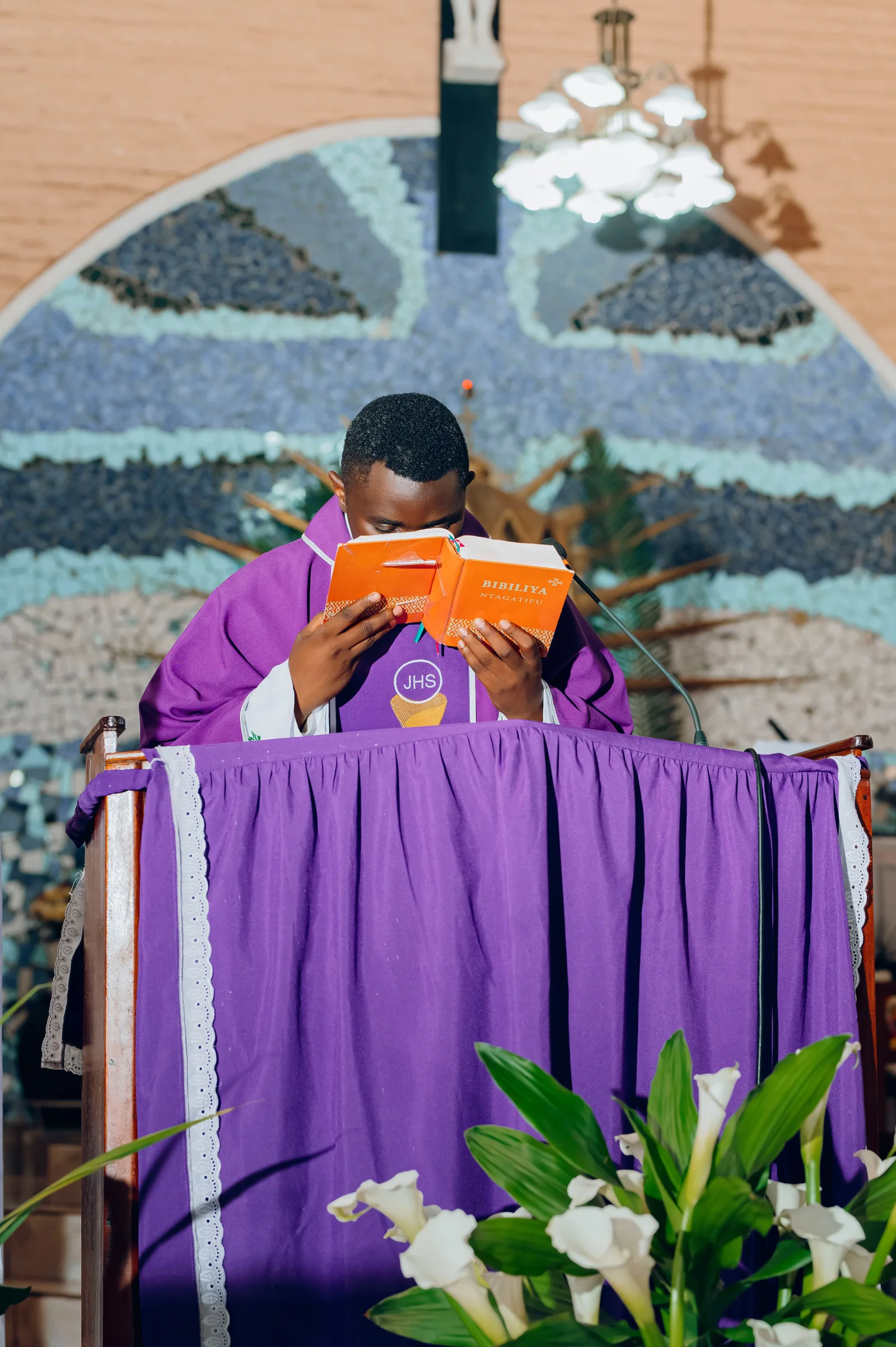 The priest is reading the bible during the mass