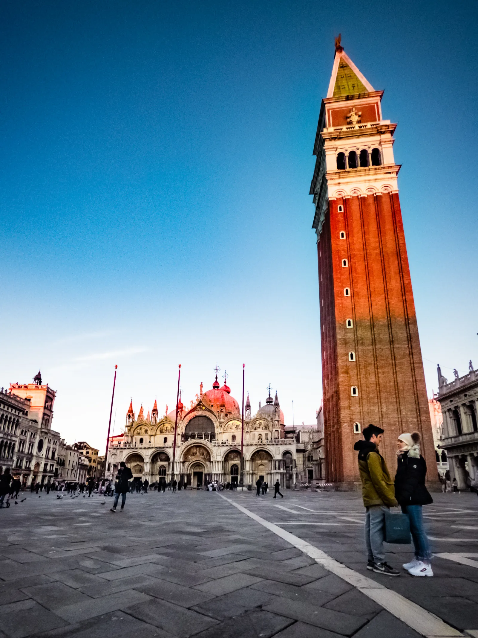 A couple of lovers holding hands at sunset in Piazza San Marco.