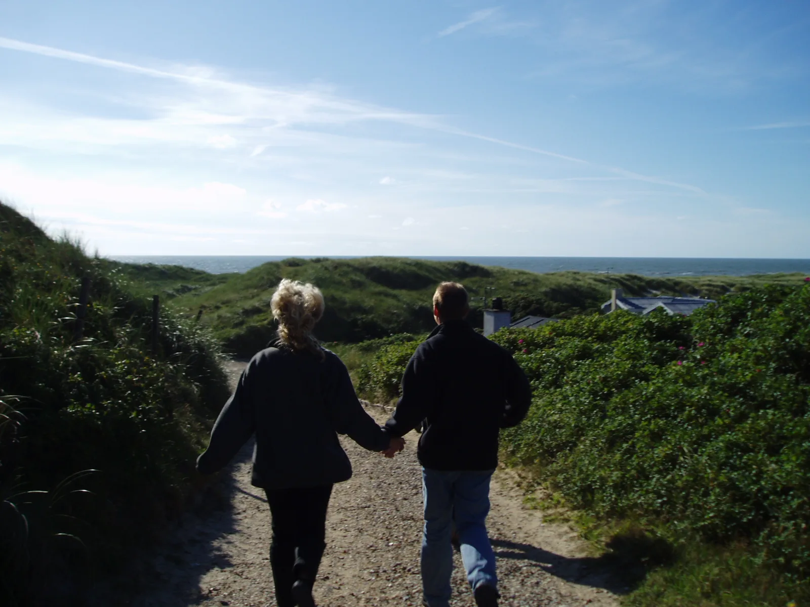 Two middle-aged people in love, running down a beach in Denmark.