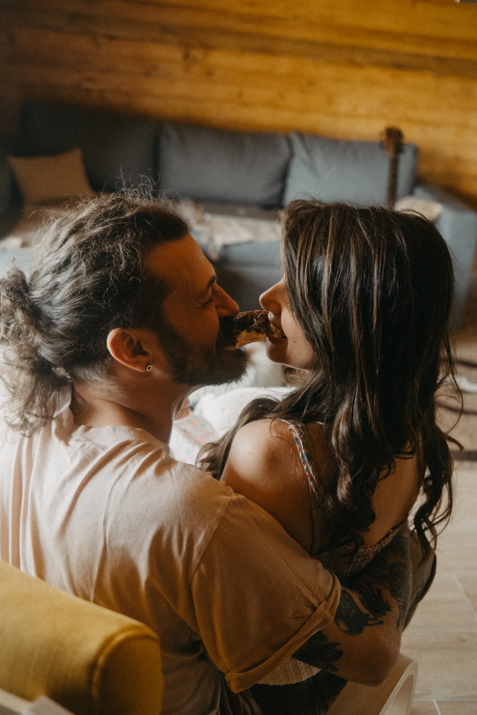 A man and woman are sitting closely in a warm room. They are smiling and enjoying each other’s company. The atmosphere looks relaxed and intimate, perfect for an evening together.