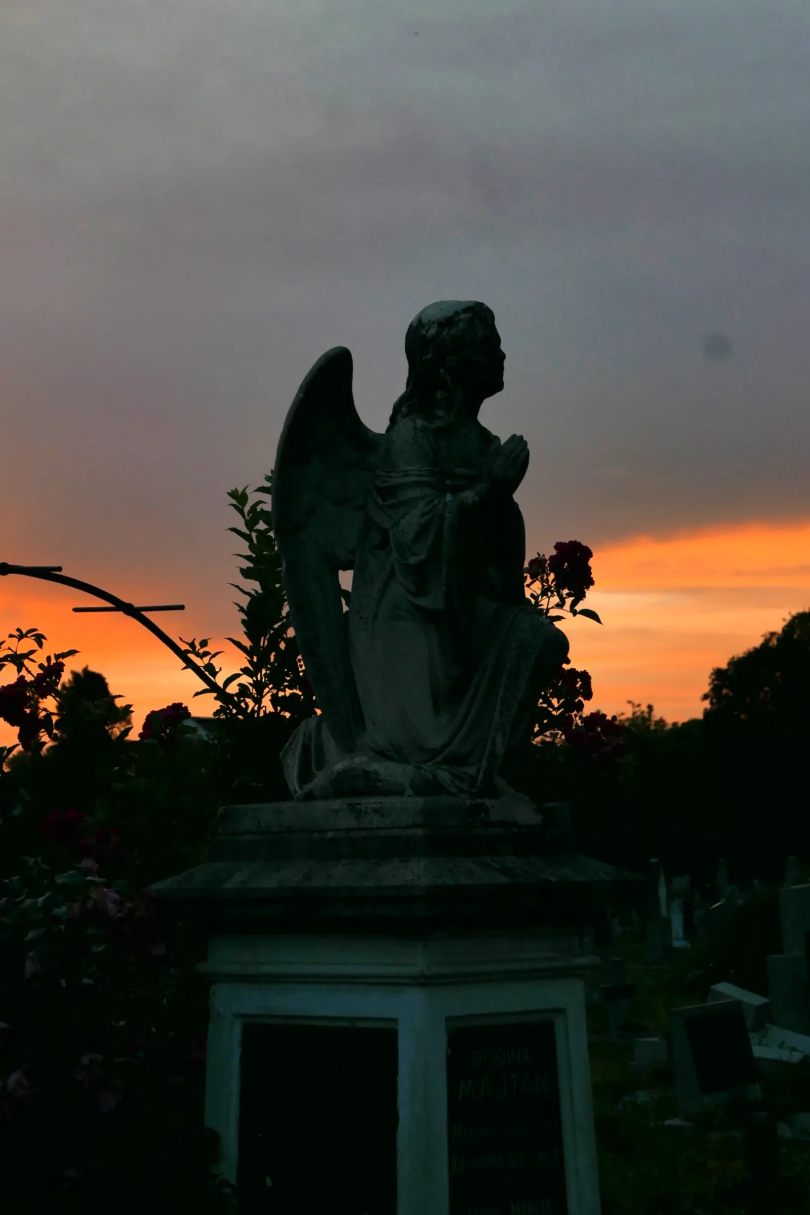 An angel statue watches silently over Almaško Cemetery as the setting sun casts its final light across the historic graves.