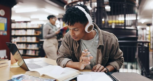 Music book and research with man in library for knowledge education and college thesis Headphones future and university with student and studying on campus for exam project and scholarship