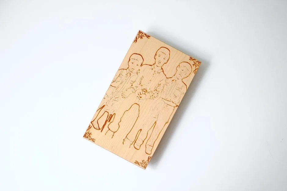 An engraved wooden plaque with a detailed family portrait on a minimalist desk.