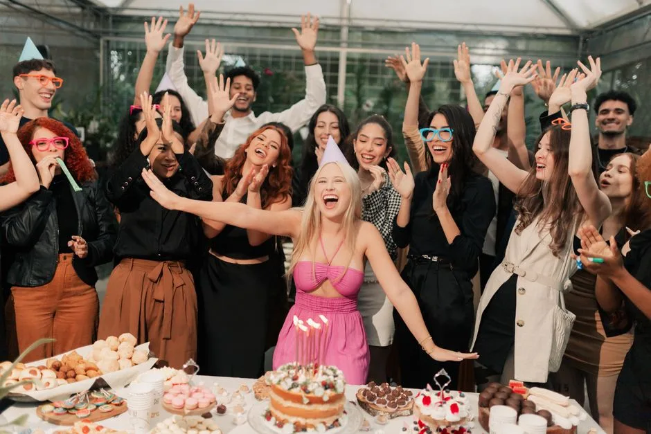 A lively birthday party indoors with friends celebrating joyfully around a cake.
