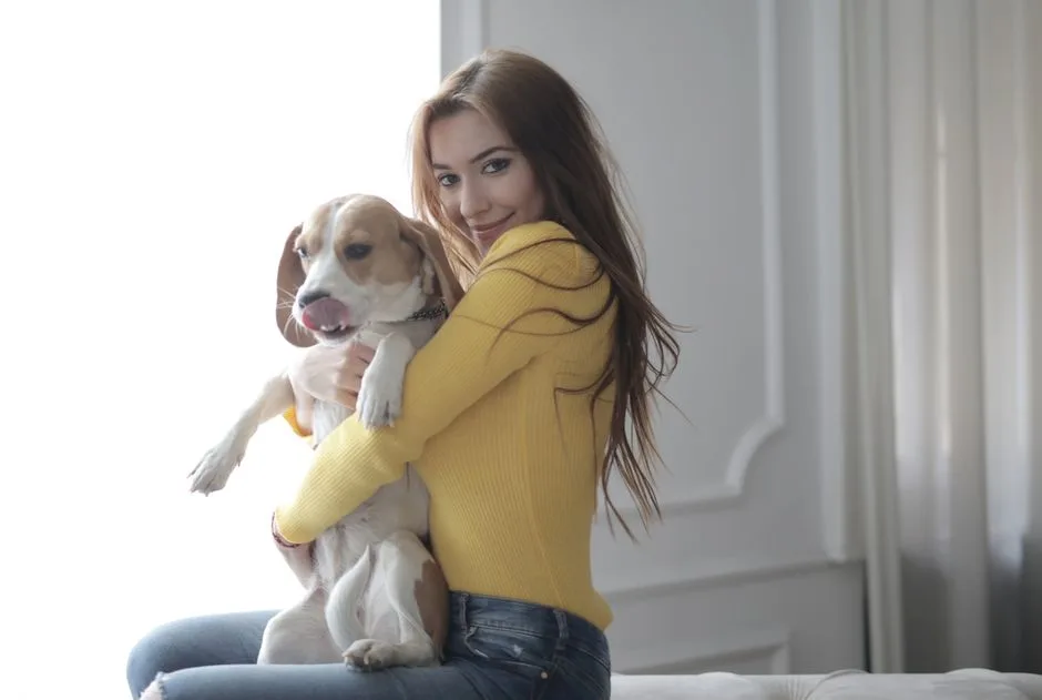 Smiling woman in yellow sweater hugging her beagle dog indoors, capturing a moment of affection.