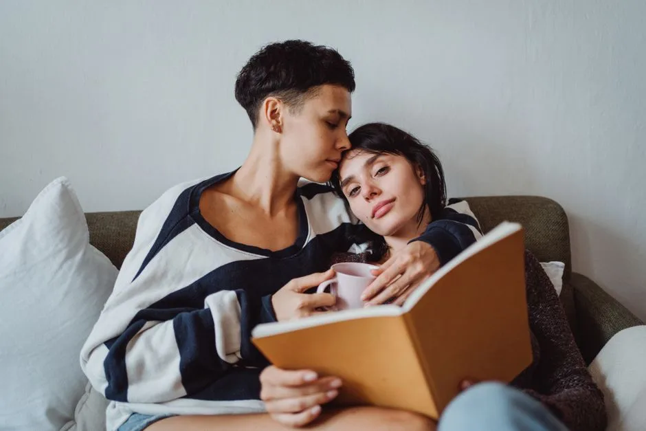 A loving couple enjoying quiet time together with a book and coffee on the sofa.
