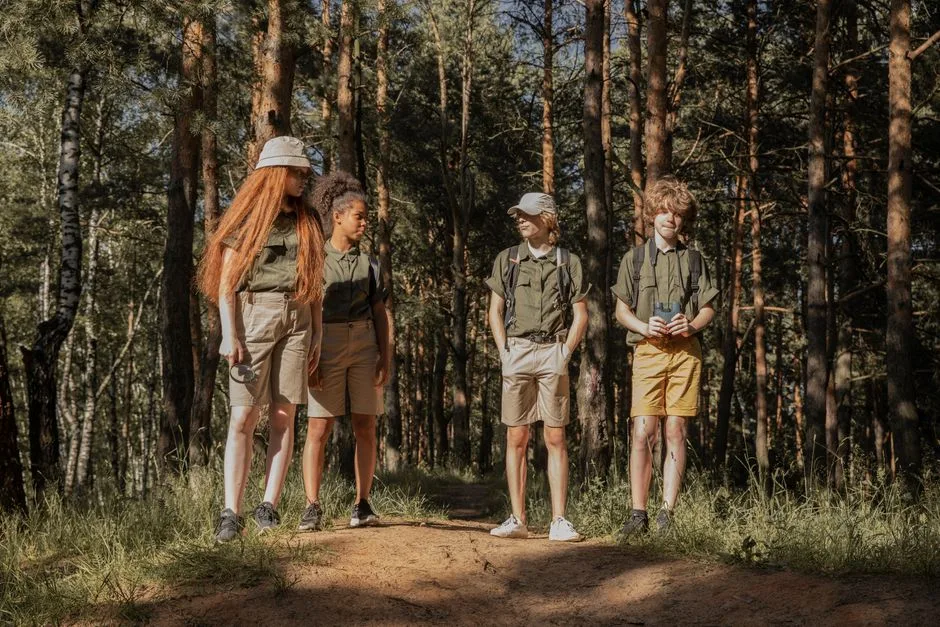 Group of teenage scouts standing on a forest trail, enjoying a sunny adventure.