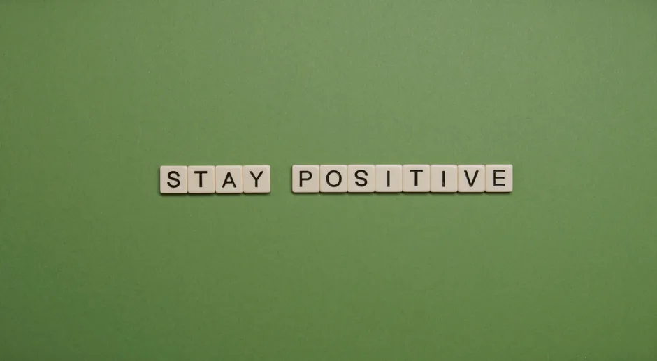 "Stay Positive" spelled with letter tiles on a green backdrop.