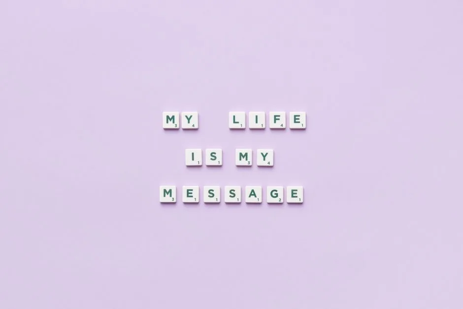 Scrabble tiles spell 'My life is my message' on a pastel purple background.