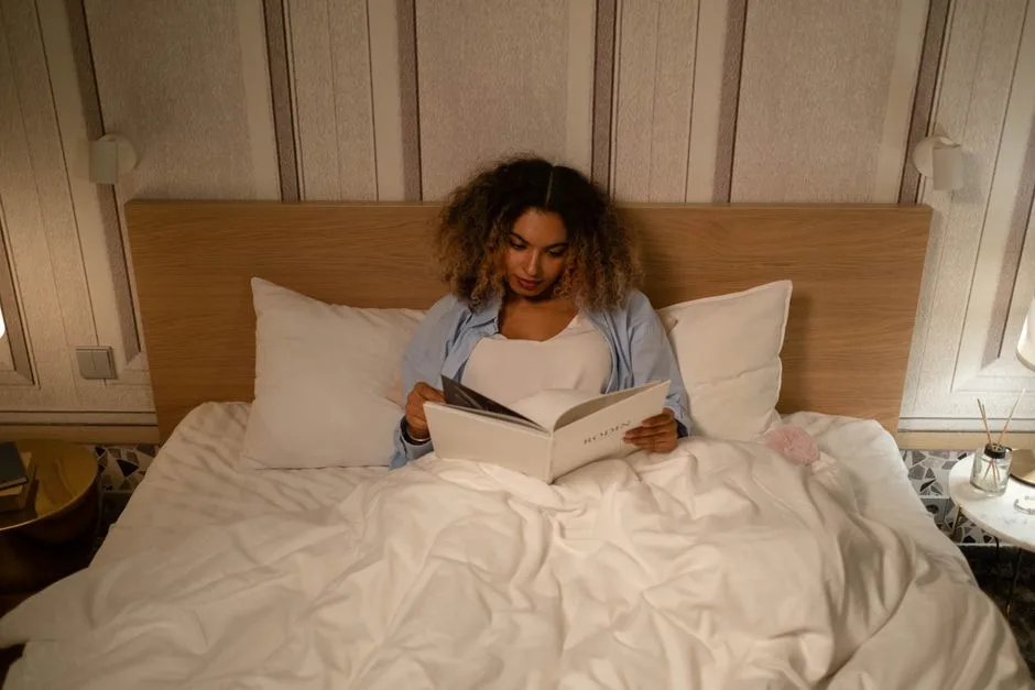 African American woman enjoys a peaceful evening reading in bed, capturing a moment of leisure and relaxation.