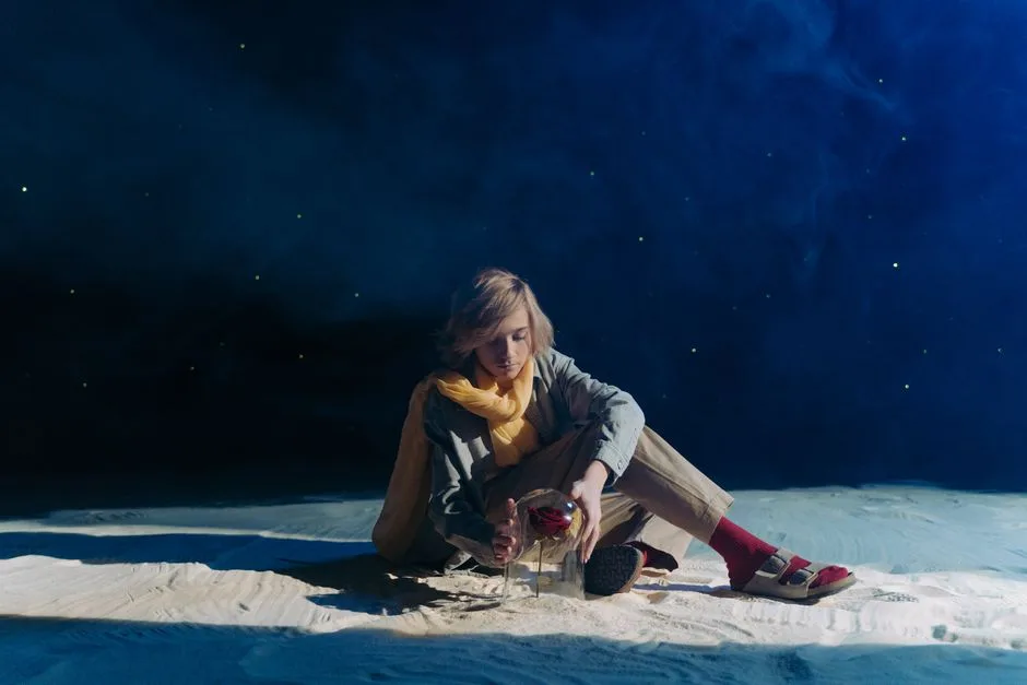 A young person in cosplay sits in a dreamy, starry setting with sand and roses.