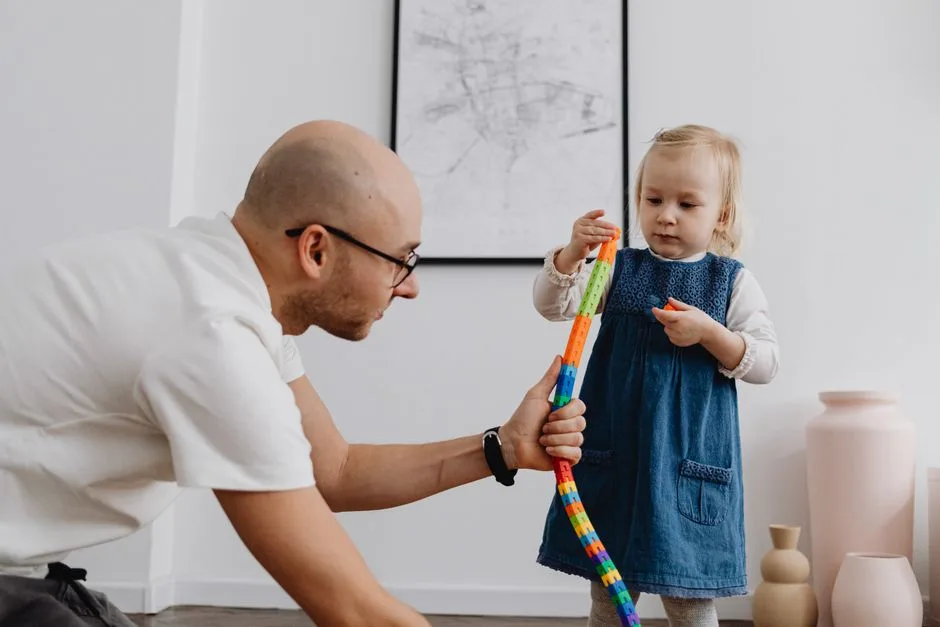 Father and daughter playing together with building blocks indoors, enhancing bonding and creativity.