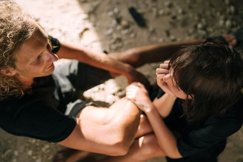 A couple sitting closely together on a sunny beach, sharing a tender moment.