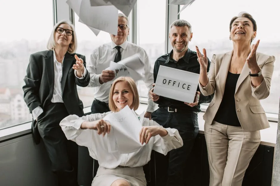 A diverse group of business professionals joyfully celebrating in an office setting, symbolizing teamwork.