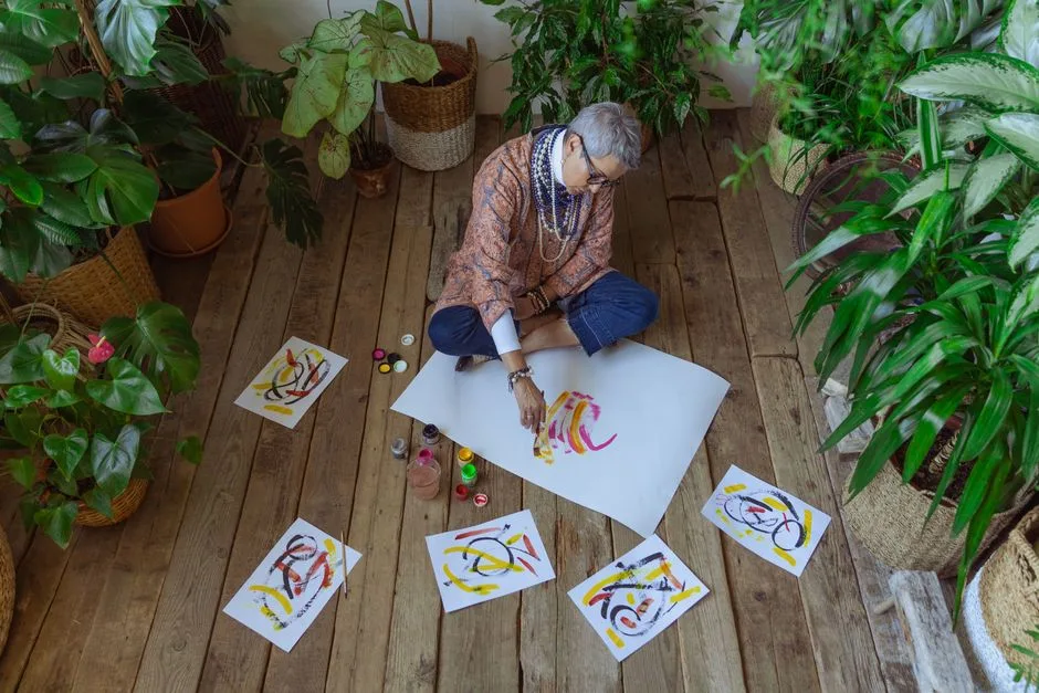 Senior woman enjoys painting surrounded by indoor plants, showcasing creativity and leisure.