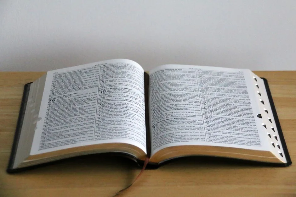 A close-up view of an open Bible on a wooden table, showcasing detailed text.