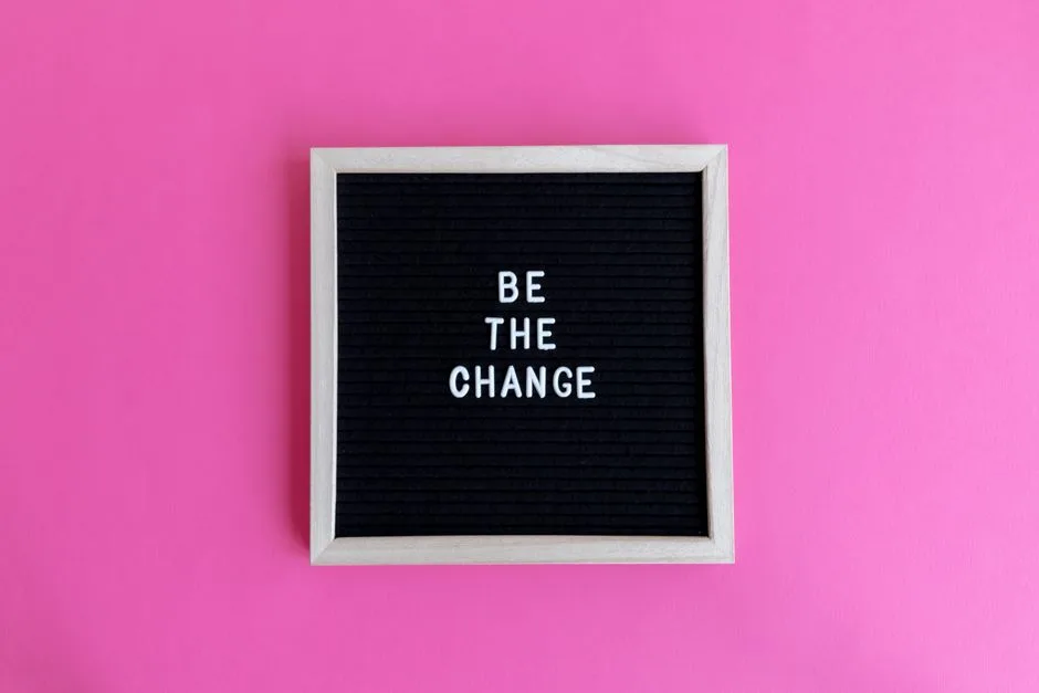 Letterboard with 'Be the Change' on a vibrant pink background.