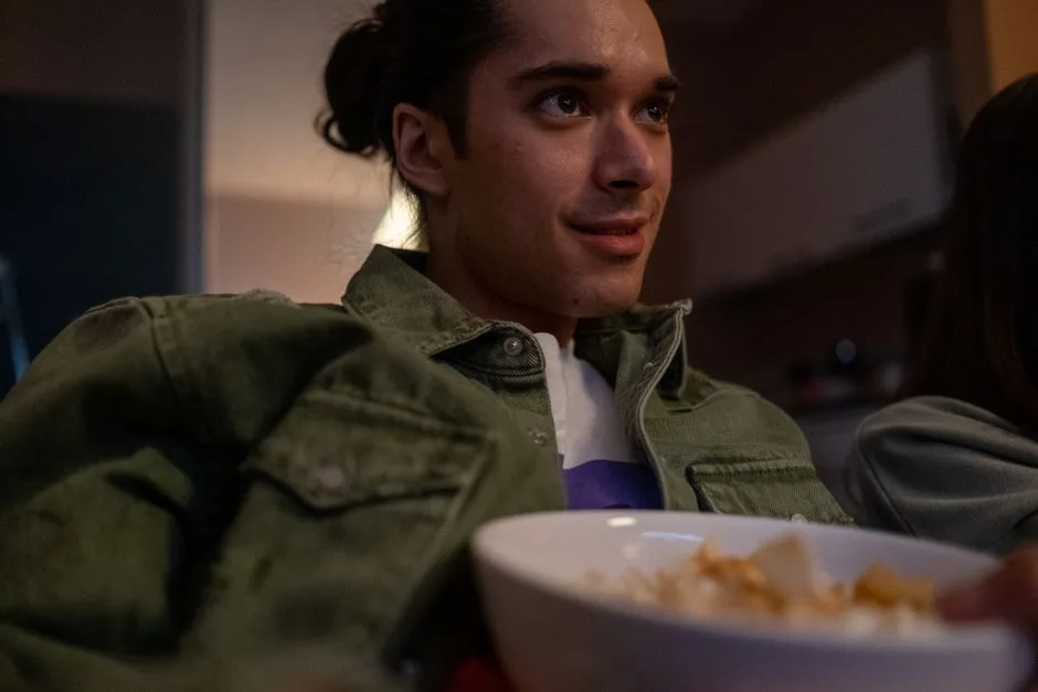 Young man relaxing indoors, watching TV and eating snacks during a cozy movie night.