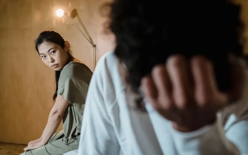 A couple experiencing tension and emotional crisis in a dimly lit room.