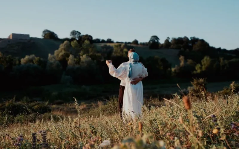 A romantic couple enjoying a peaceful moment in a scenic countryside at sunset.