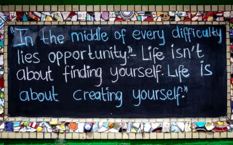 Chalkboard with inspiring quote surrounded by vibrant mosaic pieces.