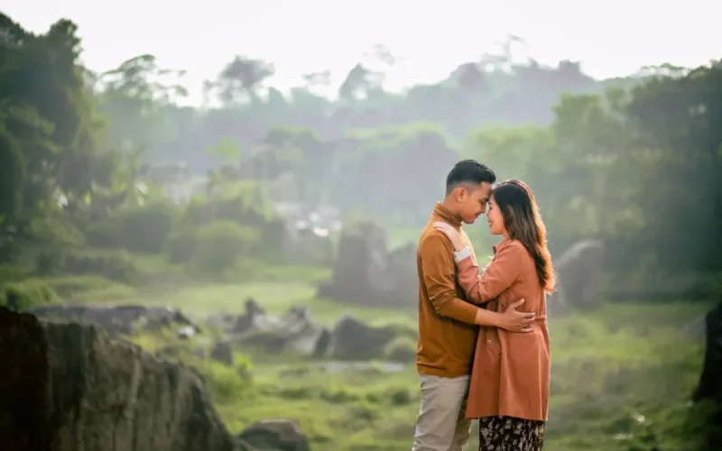 A loving couple shares a romantic moment in a green, serene park during summer.