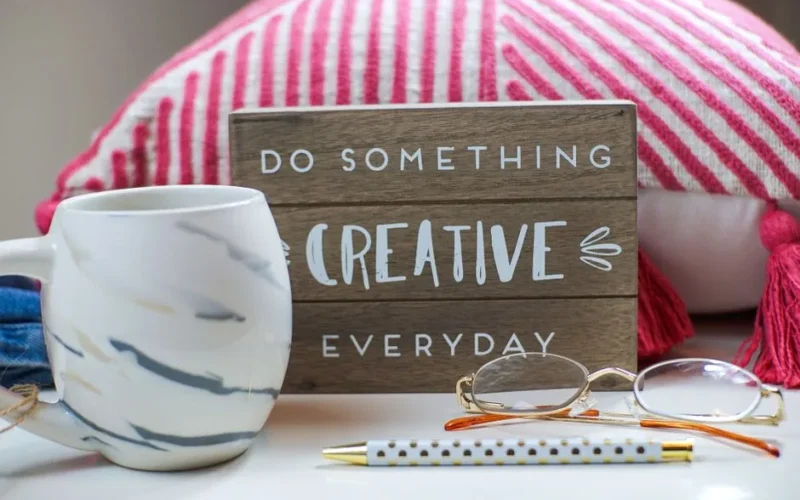Stylish desk setup with a coffee mug, eyeglasses, and motivating sign.
