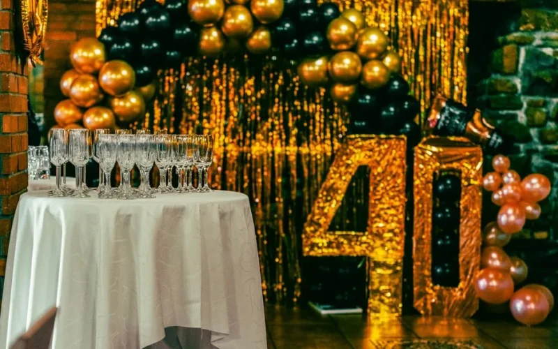 Chic 40th birthday party setting with champagne flutes, balloons, and gold glitter backdrop.