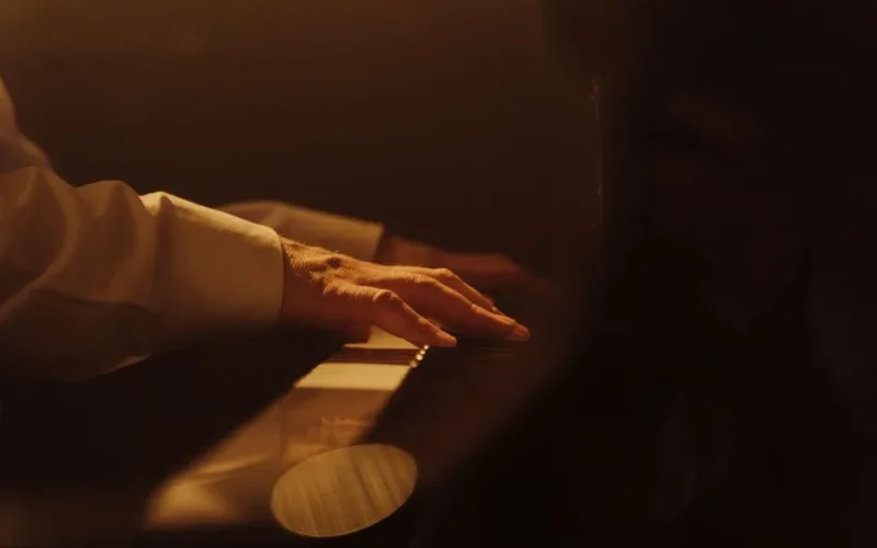 A close-up view of a hand playing a piano in warm lighting, capturing musical emotion.