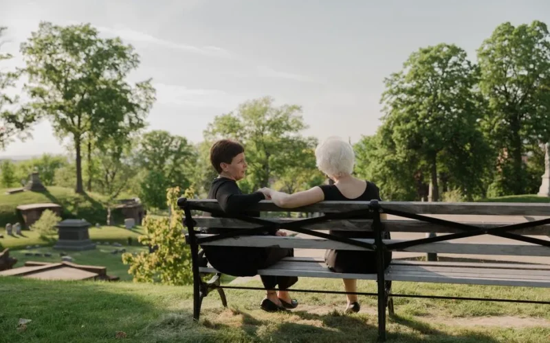 A woman in black clothes leans over pews, grieving alone in an empty church.