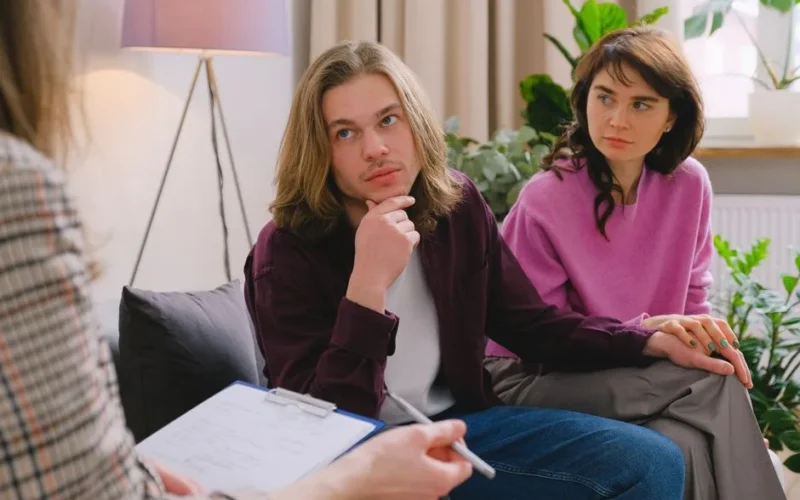 A couple holding hands during a therapy session in an office setting.