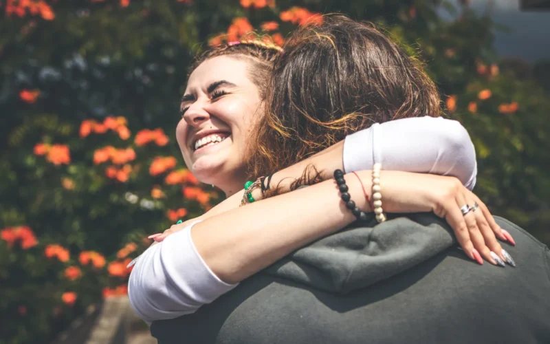 Cheerful smiling couple in love hugging in nature on a beautiful flower background.