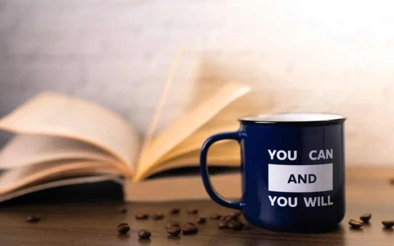 Motivational mug with an open book and coffee beans, perfect for inspiring your day.