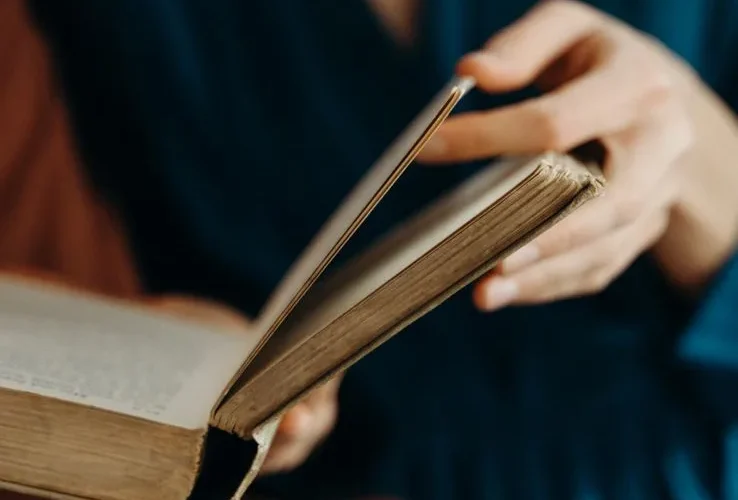 Person holding and flipping through pages of an old book.