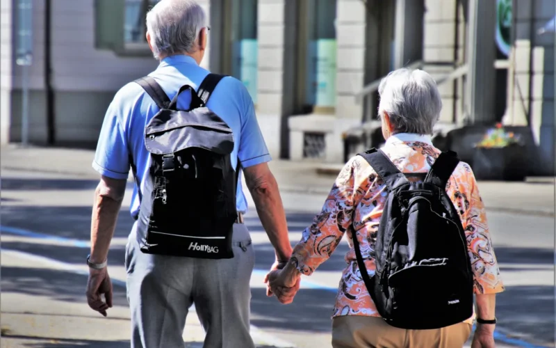 Older couple holding hands seen from behind.