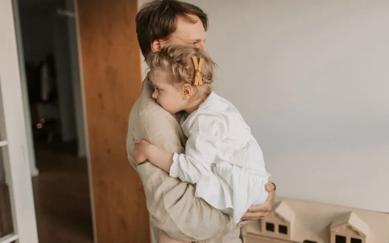 A father lovingly embraces his young daughter, showcasing tender family affection.