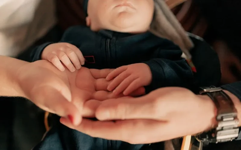Close-up of parents holding their baby's hands, symbolizing love and protection.
