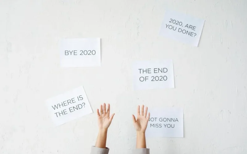 Hands reach up towards motivational text on a wall, saying goodbye to 2020.