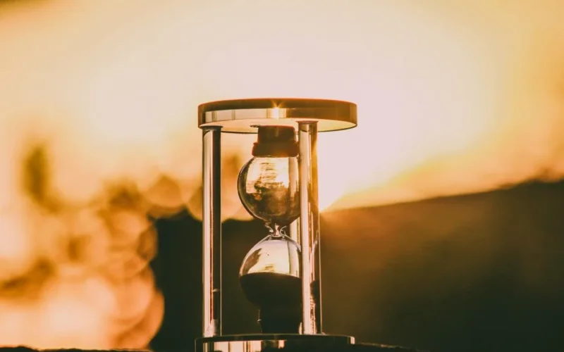Close-up of an hourglass capturing the essence of time against a sunset backdrop.