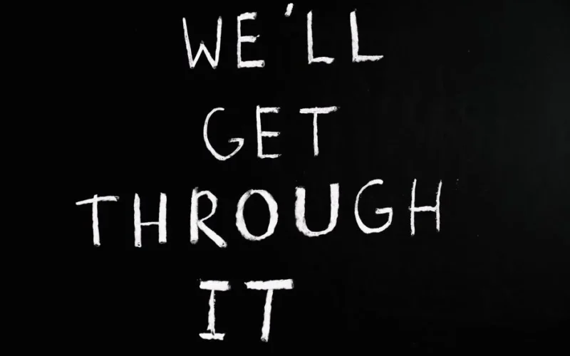 A motivational chalkboard message reading 'We'll get through it' on a black background.