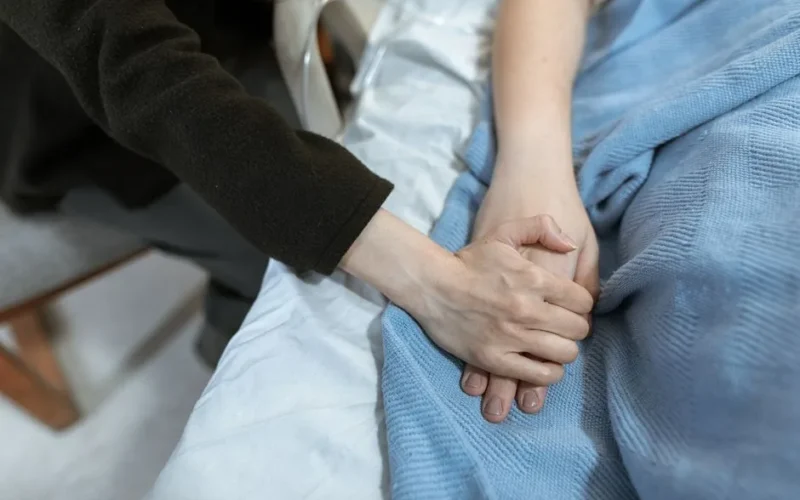 A comforting hand hold in a hospital, showcasing support and care.